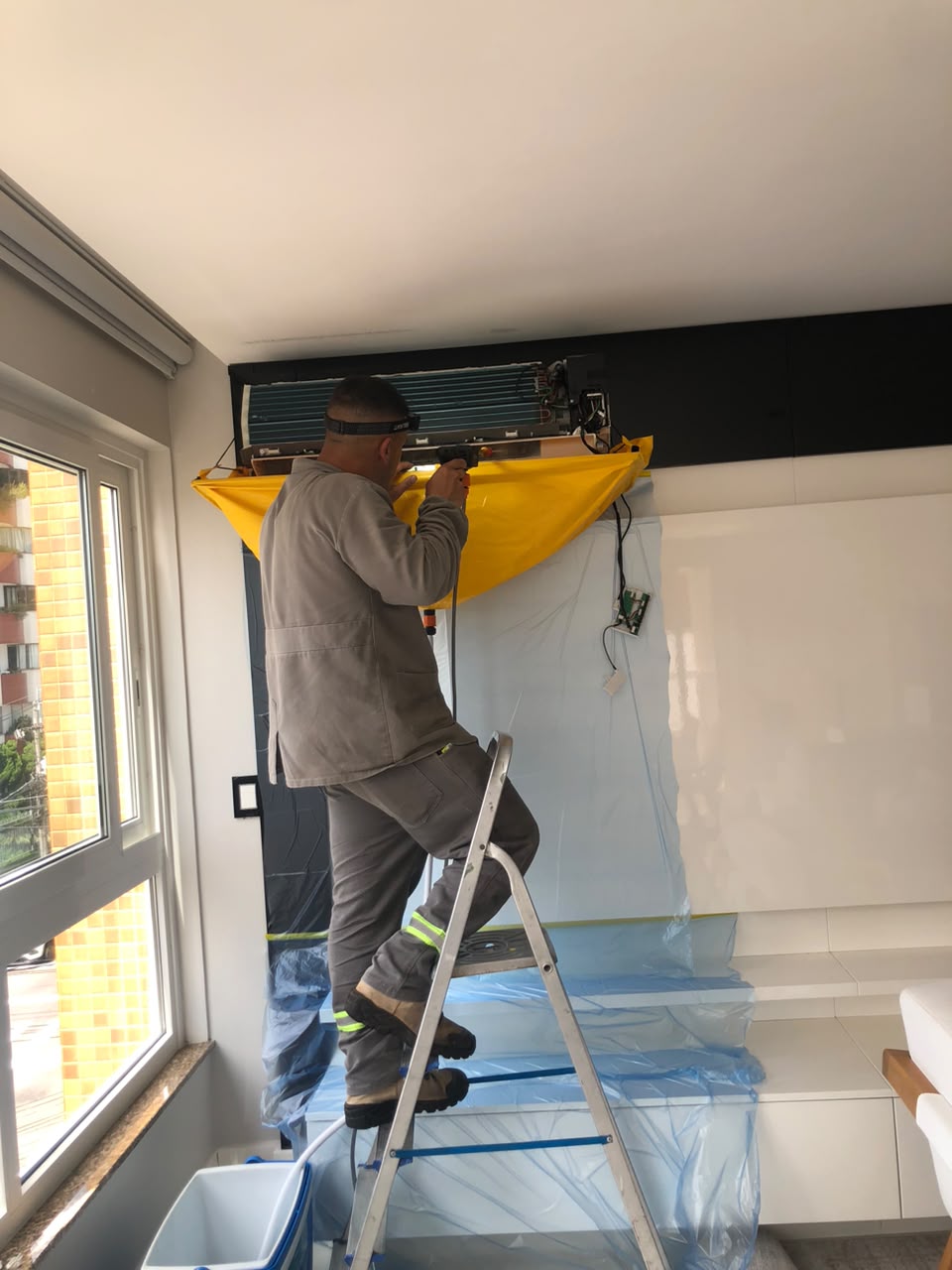 Técnico da Lerin realizando manutenção em ar-condicionado interno com proteção do ambiente