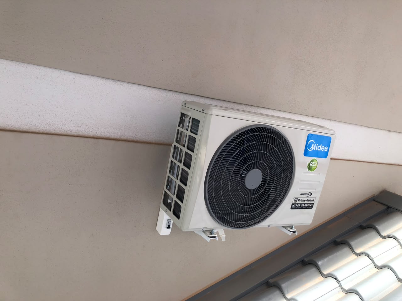 Unidade externa Midea fixada em suporte sob beiral